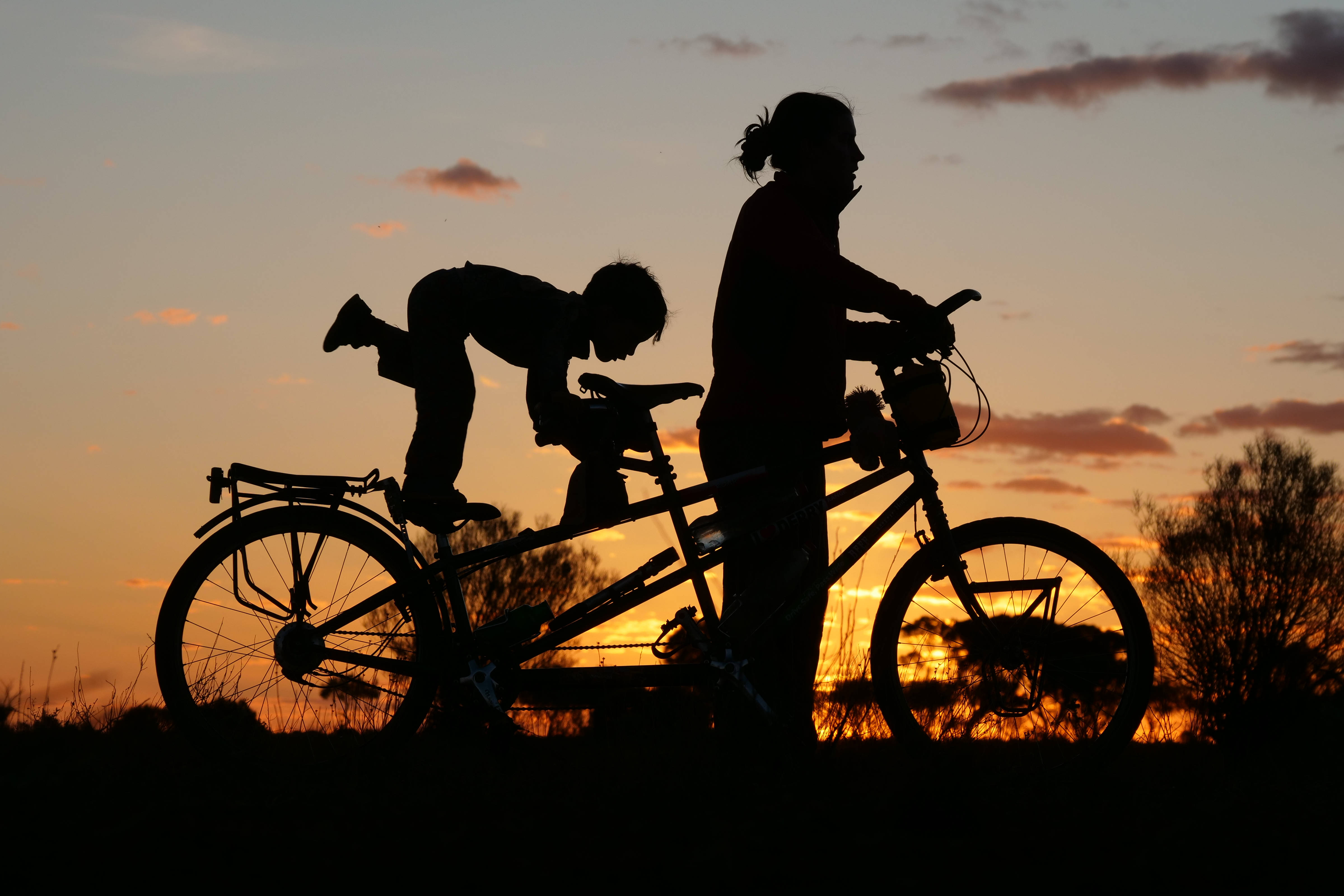 Silhouette of Wilfy and Nicola on tandem bike with sunset.