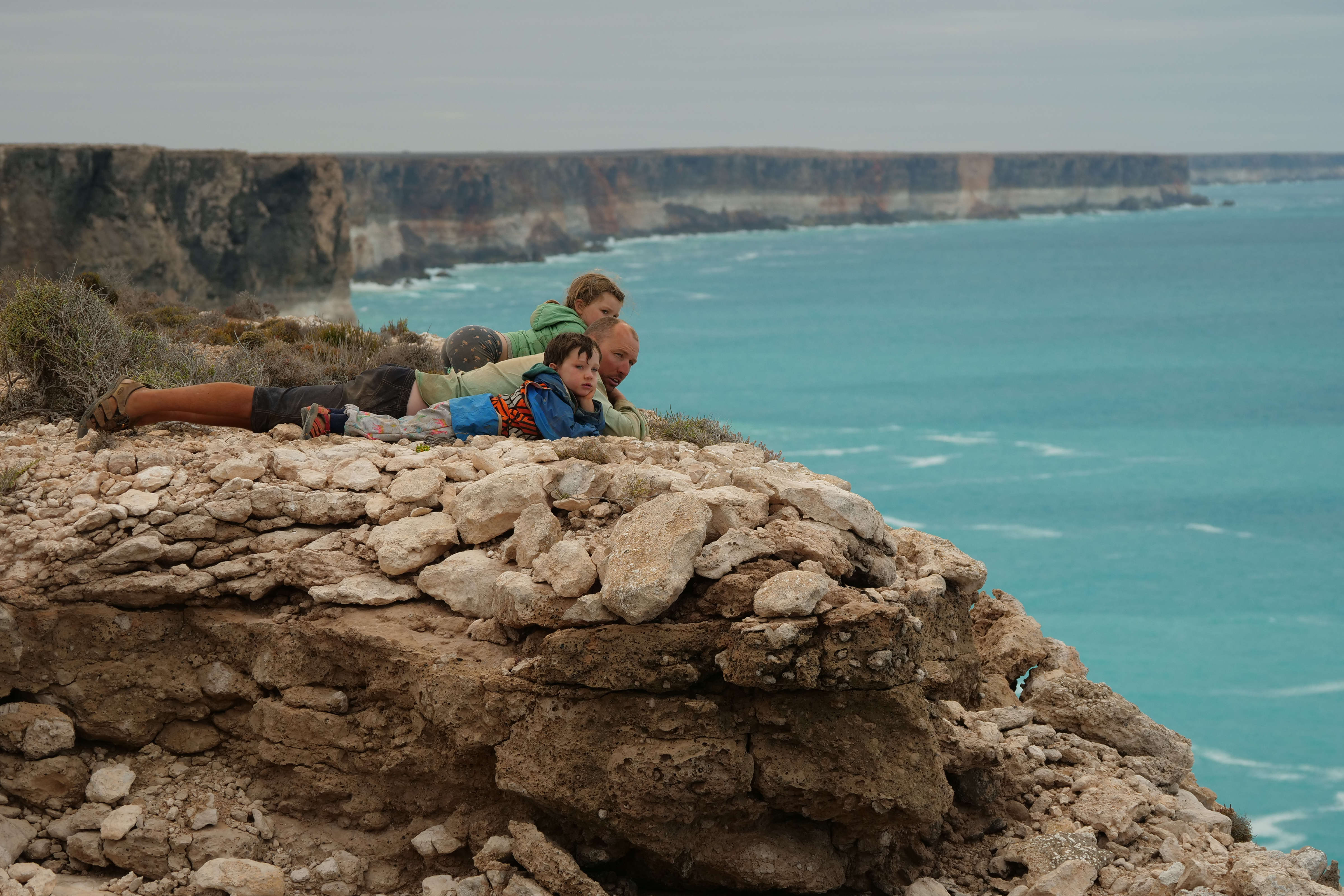 Andrew, Hope and Wilfy lying down looking over 80 metre limestone cliffs at the Great Australian Bight.