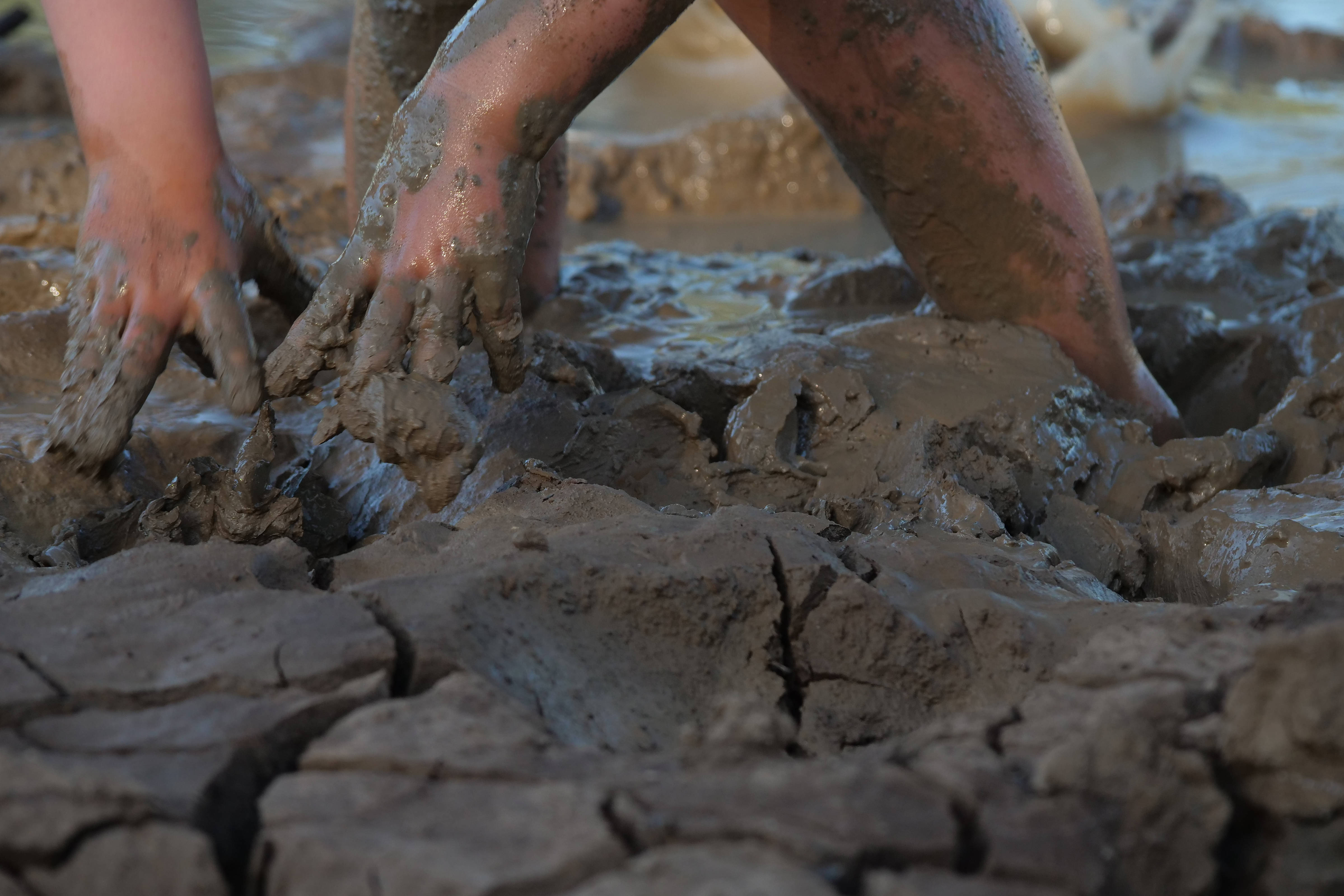 Child’s hands and feet playing in deep sticky mud.