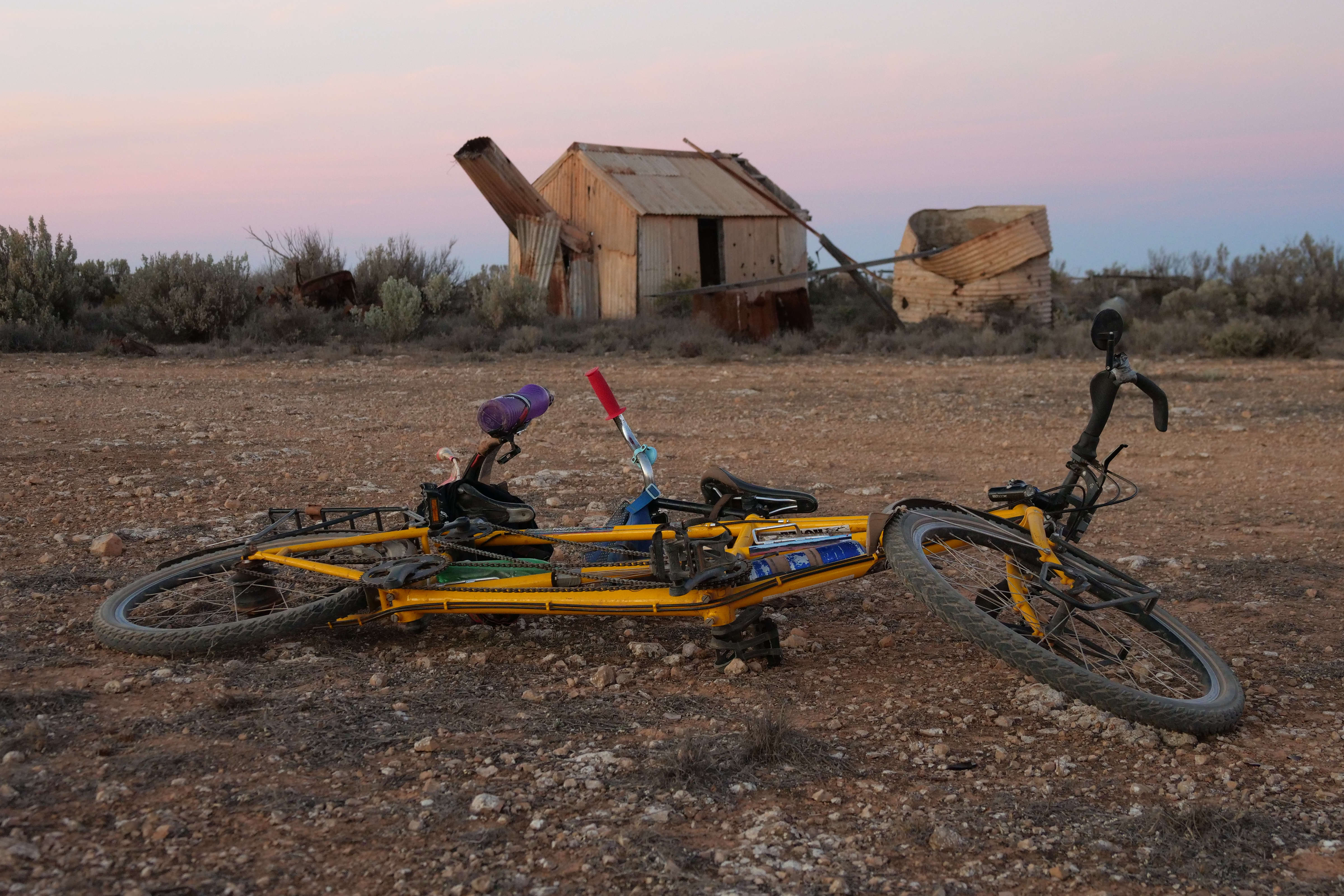 Tandem bike lying down outside abandoned shack on Nullarbor Plain.