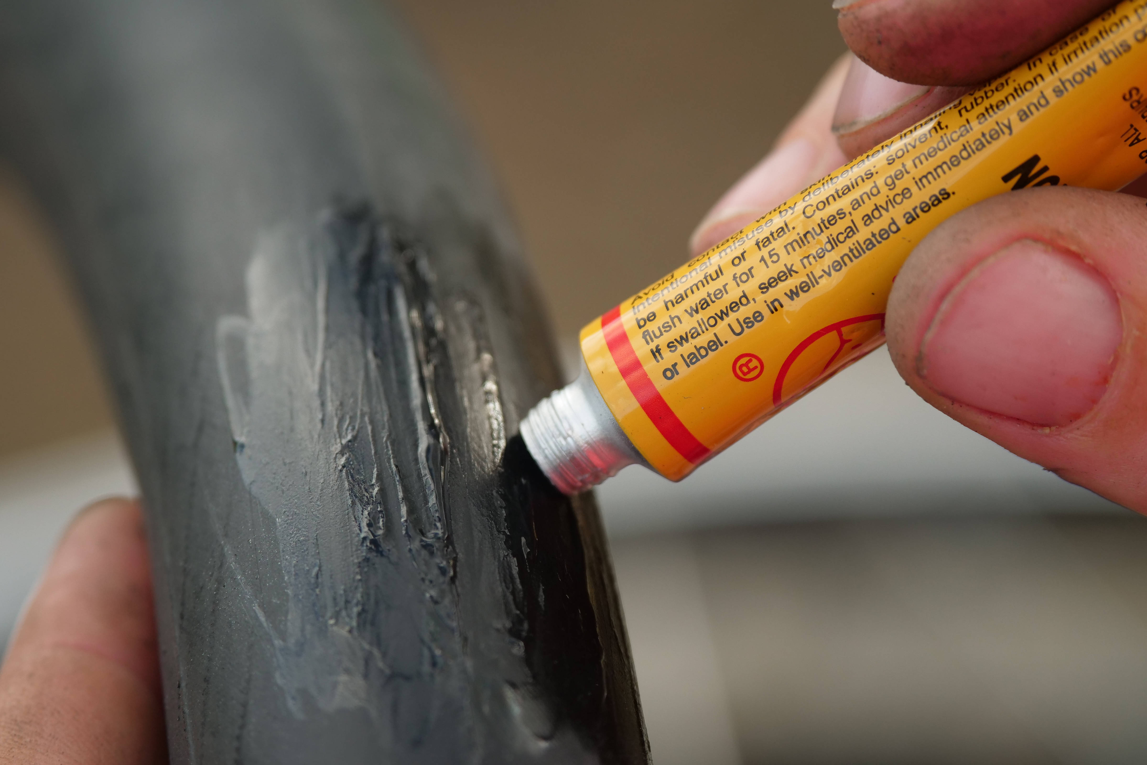 Close-up of glue being applied to a punctured tyre tube.