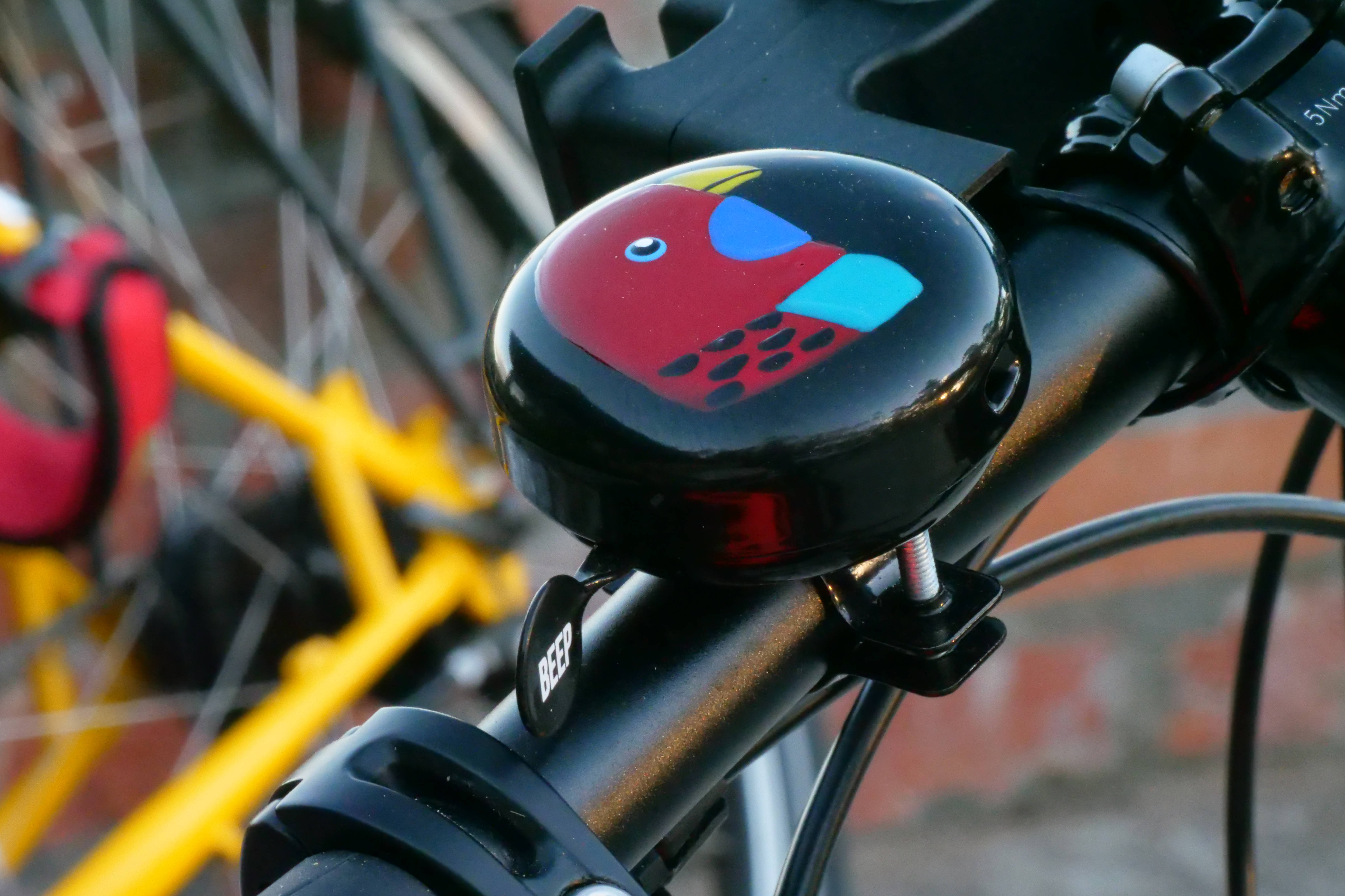 Close-up of bike bell with vibrant painting of parrot.